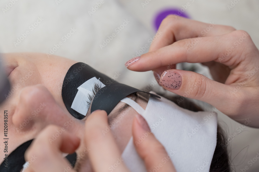 A specialist glues a client's drooping eyelid before eyelash extensions. A specialist glues a client's drooping eyelid before eyelash extensions.