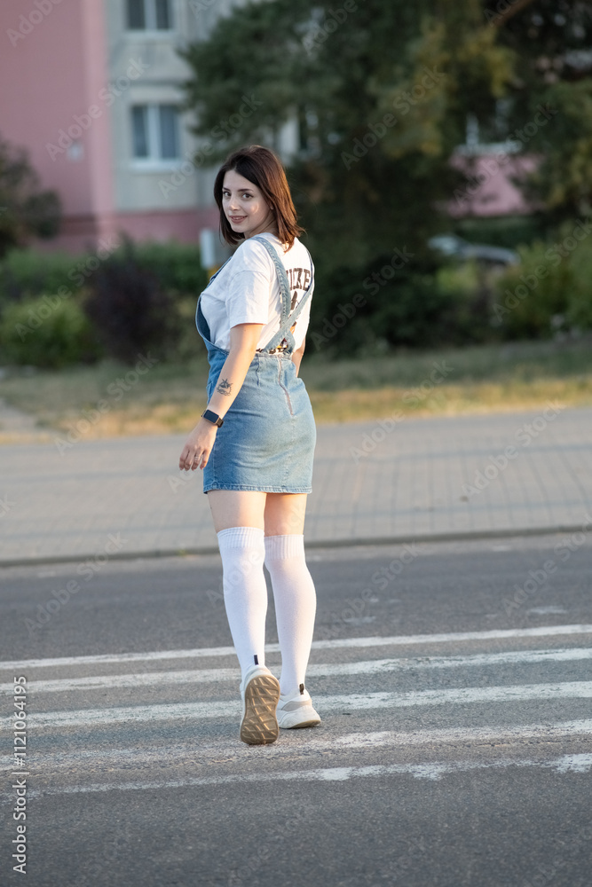 Portrait of a young beautiful dark-haired girl in a denim sundress outdoors. Portrait of a young beautiful dark-haired girl in a denim sundress outdoors.