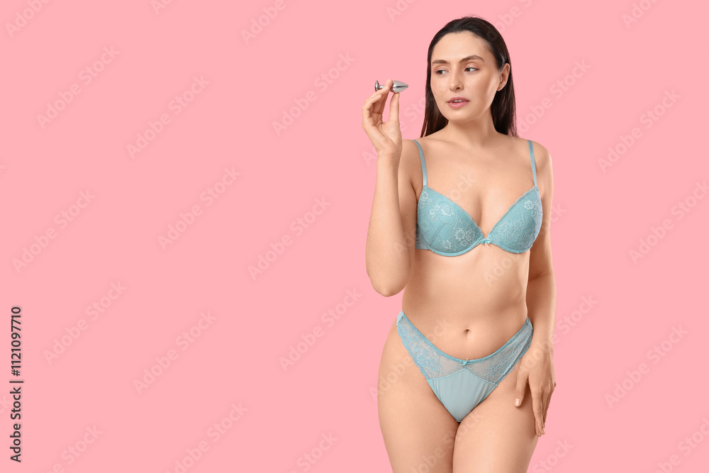 Beautiful young woman in underwear with anal plug from sex shop on pink background Beautiful young woman in underwear with anal plug from sex shop on pink background