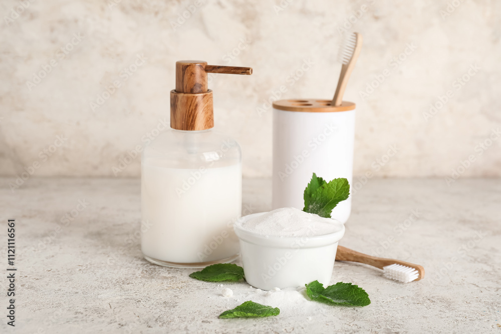 Bowl of tooth powder with leaves, brushes, holder and soap dispenser on table against white background Bowl of tooth powder with leaves, brushes, holder and soap dispenser on table against white background