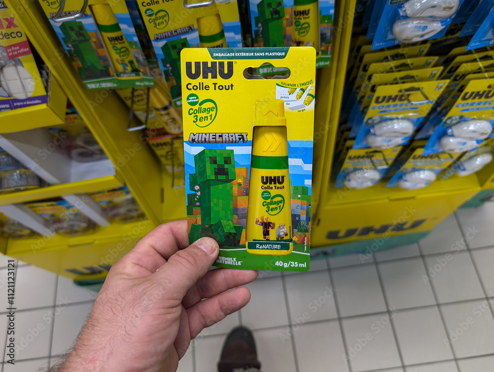 Naklejka premium France, 12 August 2024 : Hand Holding UHU Colle Tout Adhesive With Minecraft Design