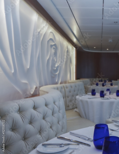 Formal and elegant ocean view Art Deco dining room restaurant onboard luxury cruiseship or cruise ship liner with set tables in classic interior design style and ceiling ambient lighting photo