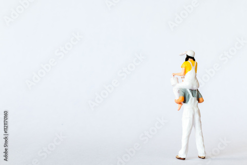 Miniature scene depicting a father carrying his daughter on his shoulders on white background