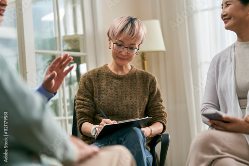 asian female social worker or medical professional facilitating a group discussion for senior people