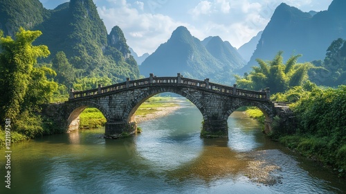 The weathered rice bridge, an ancient stone structure, spans the clear river in the middle of a mountainous region.