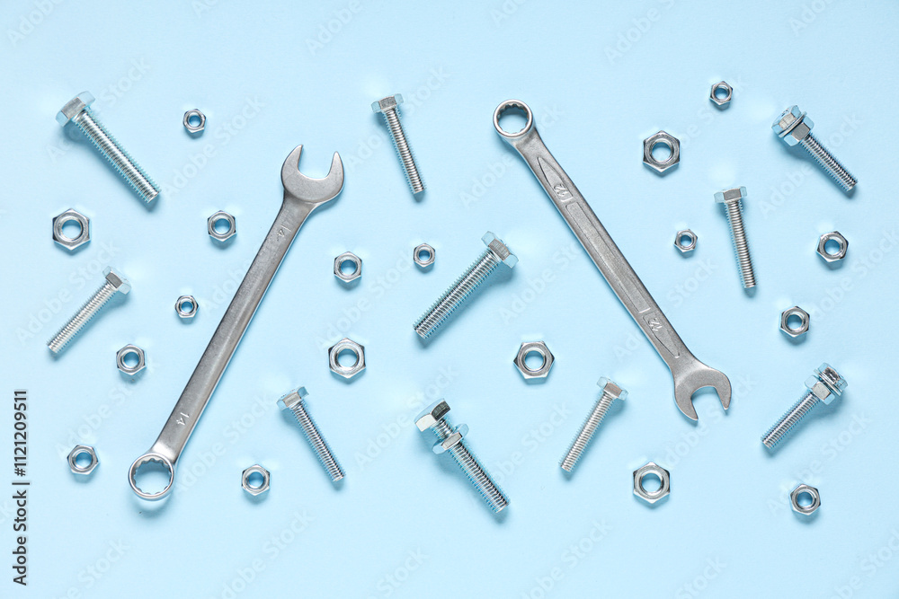 Tap bolts, chrome nuts and wrenches on blue background Tap bolts, chrome nuts and wrenches on blue background
