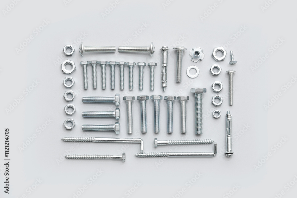 Arrangement of different tap bolts, screws and chrome nuts on grey background Arrangement of different tap bolts, screws and chrome nuts on grey background