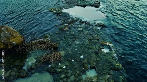 A rocky shoreline with clear water and visible stones at low tide.
