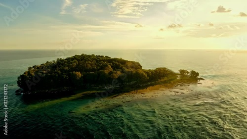 Aerial view of a serene island surrounded by calm waters at sunset.