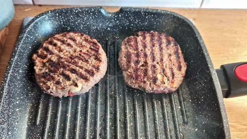 Burger patties cooking in a gridle pan, pullback close up view photo