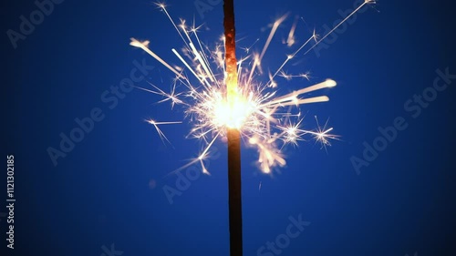 Burning sparkler on blue background, macro, 4K