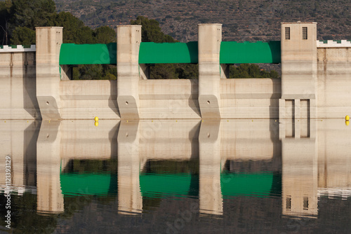 Muro de contención en el embalse de Beniarres con reflejos y bajo nivel de agua por la sequía y cambio climático, España photo
