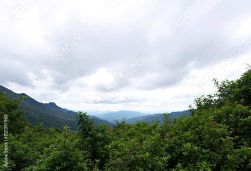 A scenic view of a mountainous landscape with a cloudy sky in the background