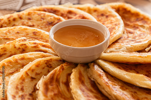 Obraz na płótnie Msemen with crispy edges and soft layers, paired with golden honey, ready to be enjoyed on a wooden cutting board. w salonie