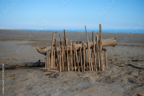 Construction of driftwood sticks placed on a sandy beach. Fine motor skills with hands, and fingers. Creativity and mindfulness in the natural environment. Copy space. 