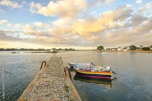 Pont qui avance au milieu de la mer avec des barques colorées amarrées et un ciel legerement nuageux. Maison de Nichtarguer dans le département Morbihan sur la ria d'Etel en Bretagne, à Saint Cado photo