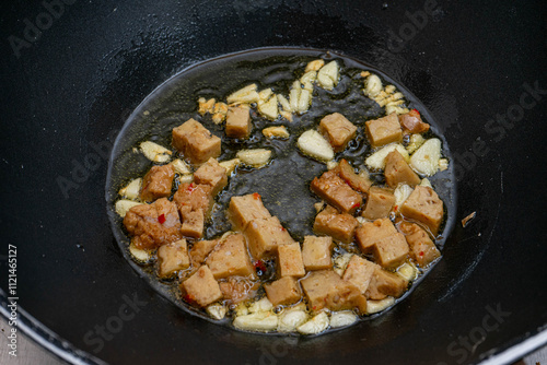 Golden-brown seitan cubes sizzling in a frying pan with garlic and olive oil. A healthy, plant-based protein meal idea, perfect for vegan or vegetarian cuisine concepts.