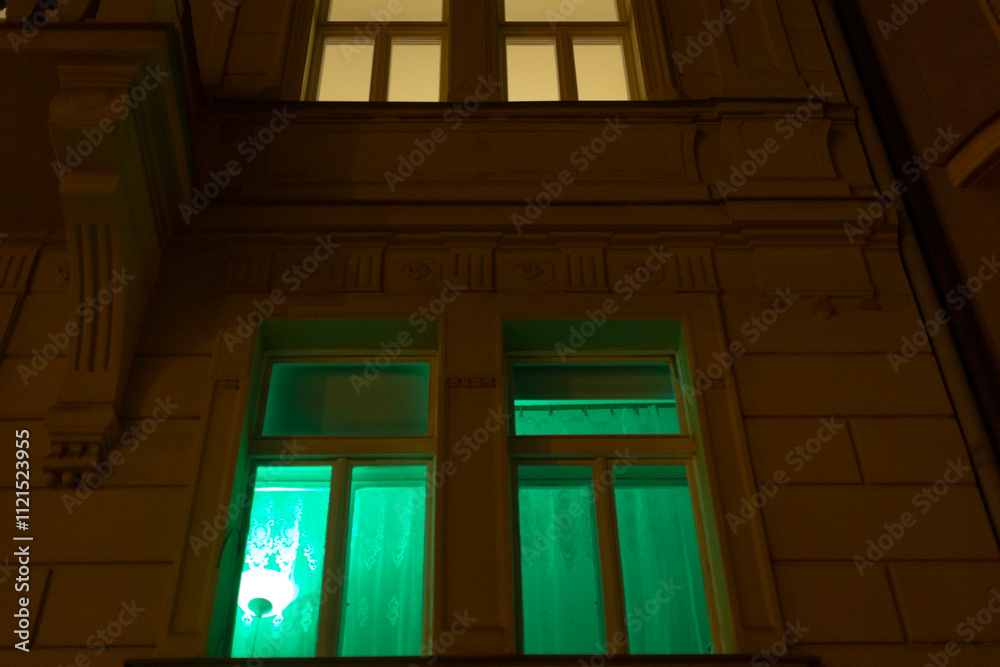 Obraz premium A large window emits a vibrant green light, casting an enchanting glow in the surrounding area, enhancing the nighttime atmosphere
