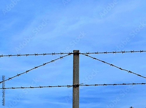 Barbed wire on a pole against the sky