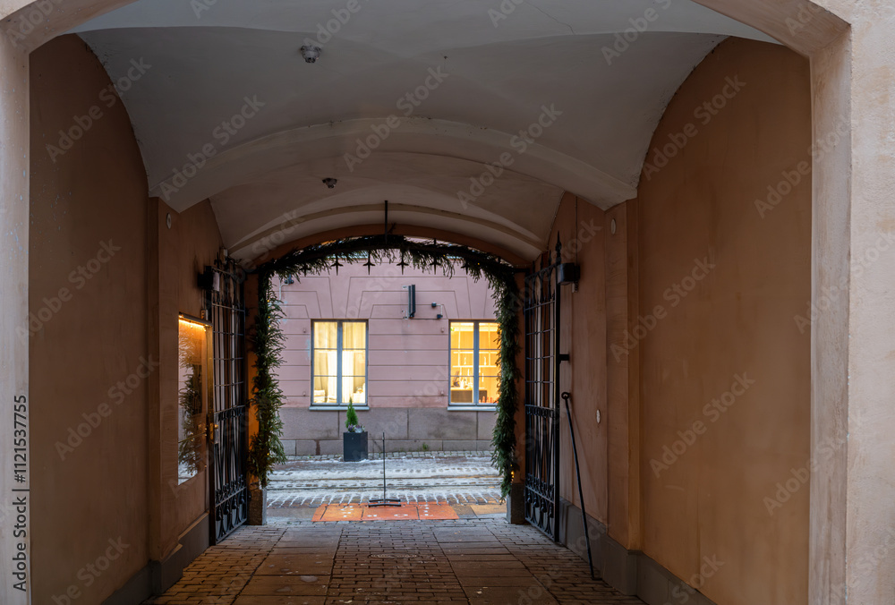 Fototapeta premium Cozy arched passageway with view of illuminated windows. 