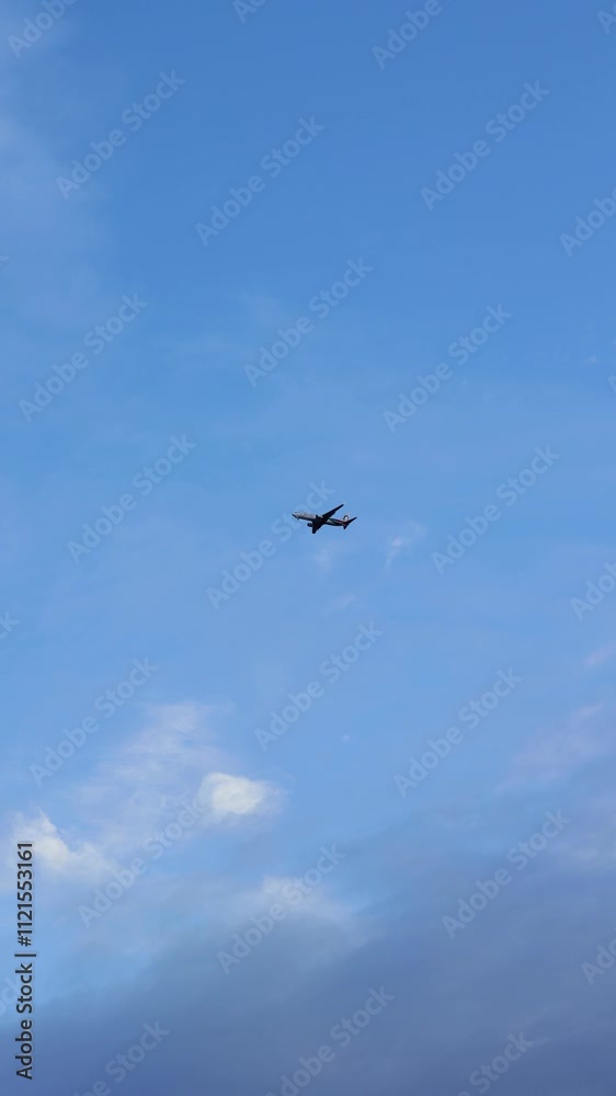 Vertical shot of a Airplane flies through the blue sky on a cloudy day Vertical shot of a Airplane flies through the blue sky on a cloudy day