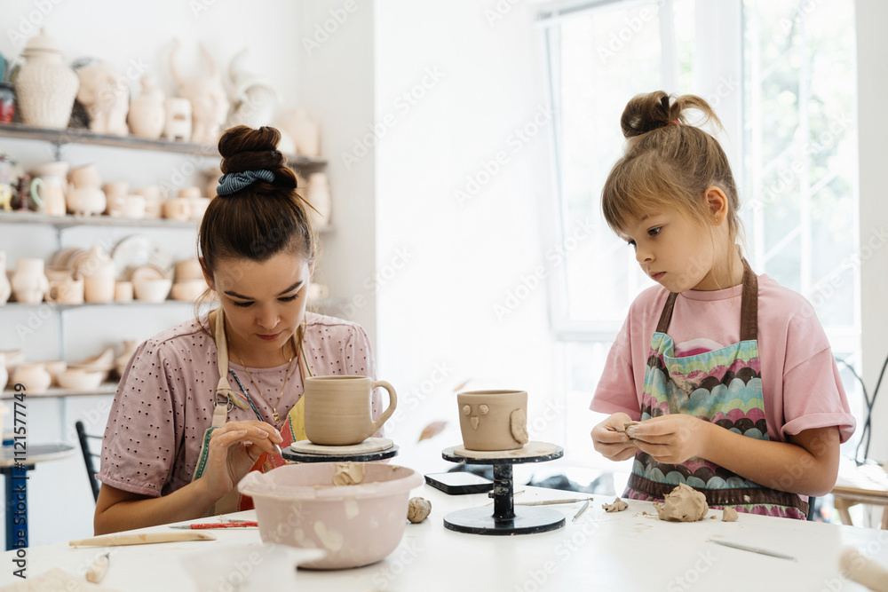 An adult and child create pottery together in a bright studio An adult and child create pottery together in a bright studio