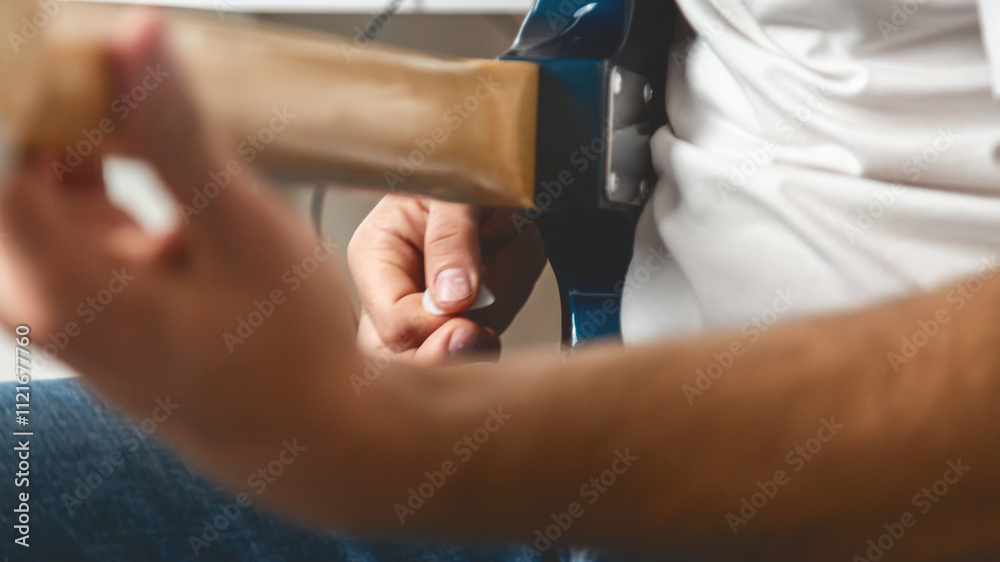 Obraz premium Guitar music. The performer plays. Practice chords. Male performer hands with fingers studying melody of song on electric string guitar fretboard indoors.