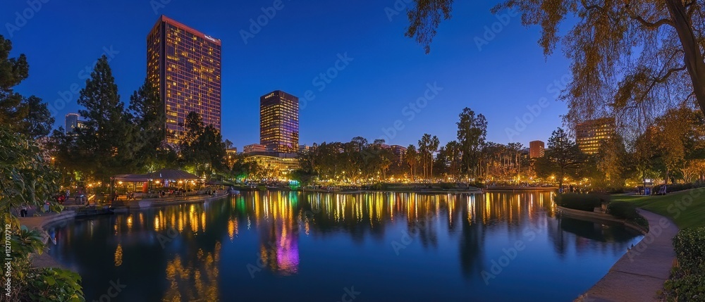 Fototapeta premium Vibrant cityscape glowing under clear night sky, skyscrapers illuminated by colorful lights, reflections shimmering in calm water, bustling streets creating modern harmony with urban beauty and