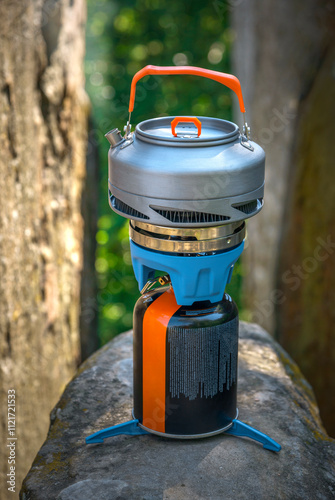 Camping kettle on a tourist gas stove against the backdrop of cliff photo