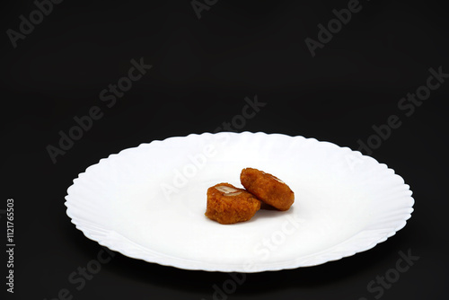 A white plate features two pieces of the classic Gujarati sweet called Mohanthal photo