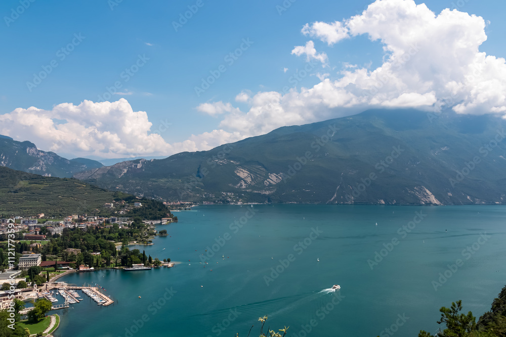 Panoramic view of idyllic lakeside town Riva Del Garda at lake Garda, Trentino, Northern Italy. Seen from Ascensore Panoramico on Bastione di Riva surrounded by mountains of Garda Hills. Summer travel Panoramic view of idyllic lakeside town Riva Del Garda at lake Garda, Trentino, Northern Italy. Seen from Ascensore Panoramico on Bastione di Riva surrounded by mountains of Garda Hills. Summer travel