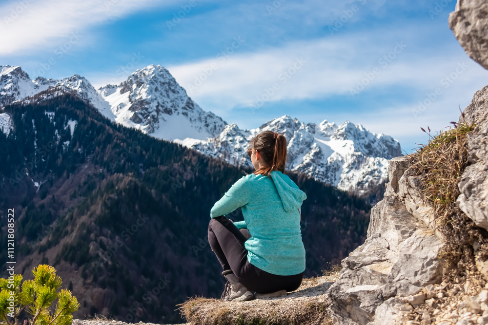 Hiker woman with panoramic view of snow capped mountain peaks of Julian Alps seen from Monte Nebria, Friuli Venezia Giulia, Italy. Wanderlust in alpine wilderness in early spring. Positive emotions Hiker woman with panoramic view of snow capped mountain peaks of Julian Alps seen from Monte Nebria, Friuli Venezia Giulia, Italy. Wanderlust in alpine wilderness in early spring. Positive emotions