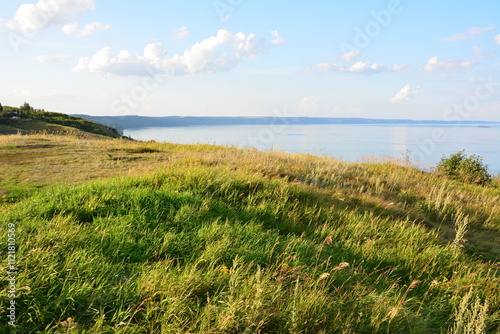 a grassy field with a lake in the background in the sunset copy space