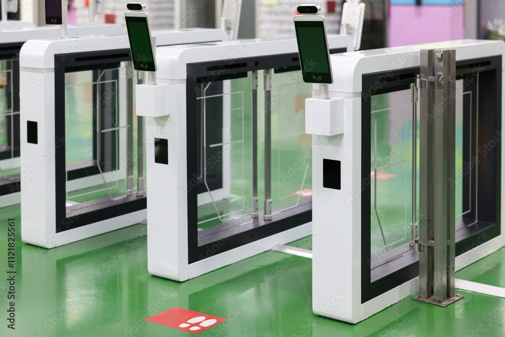 Three white and black gates with a green sign on the floor. Security turnstile at school gate. Three white and black gates with a green sign on the floor. Security turnstile at school gate.