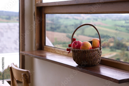 Apples in a basket placed on a wooden counter in the living room, looking out over a mountain view.