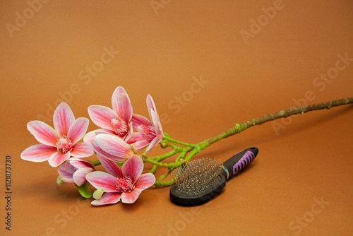 Massage comb for combing women's hair. Plastic brush with metal corners for detangling hair. A bouquet of lily flowers. on the background. Close-up.	