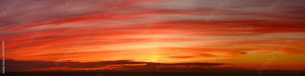 Obraz premium Wide panorama of a glowing orange striped sunset sky
