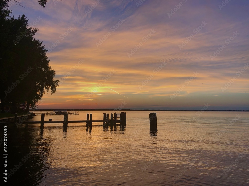 Fototapeta premium peaceful sunset over lake with reflection in water with dock