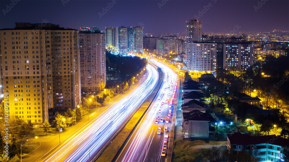 Fototapeta premium Night cityscape with illuminated streets and modern high-rise buildings, showcasing urban life and vibrant activity during the evening hours.