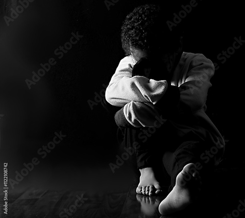 boy in poverty being bullied at school with depression no help crying alone and all by himself on black background with people stock photo stock image