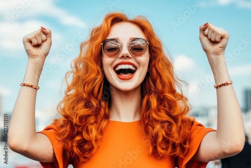 Joyful young caucasian female with red hair celebrating outdoors on a sunny day