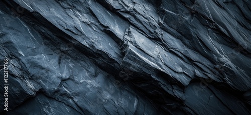 Textured dark slate rock surface, intricate patterns and shadows, cool tones, natural geological formation, copy space for text