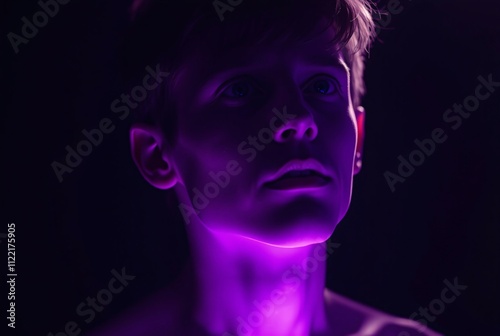 Mysterious Gaze in Purple Light:  A close-up portrait of a young man bathed in a mesmerizing purple glow, his gaze directed upwards, hinting at contemplation, mystery, and the allure of the unknown.  photo