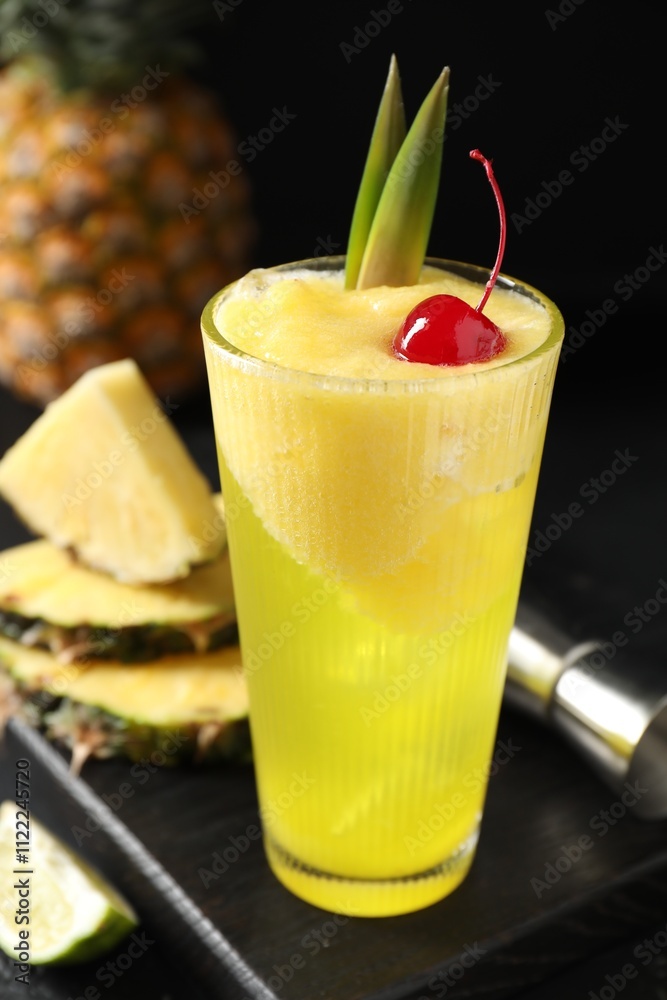 Fototapeta premium Tasty pineapple cocktail with cherry in glass on black table, closeup