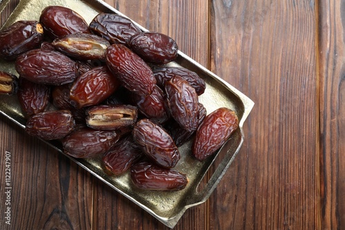 Photos Many tasty dried dates on wooden table, top view. Space for text