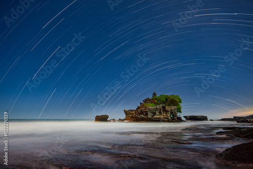 Tanah Lot temple, Bali, Indonesia, motion blur in waves and round star trails over le temple at night photo