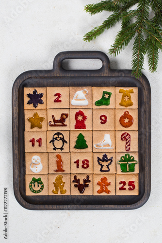 25 Little square cookies with colored marmalade filling in the shape of a Christmas Advent Calendar. On a wooden plate. Top view