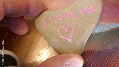 Drawing pink Valentine heart on heart shaped rock