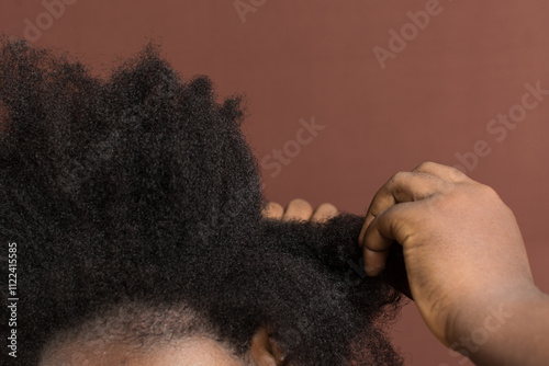 detangling Black afro coily dry hair, Type 4c hair that is dry with a brown background photo