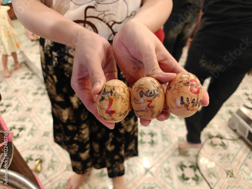 a person holding three eggs lucky number from Wat Mahabut (Mae Nak Phra Khanong) in their hands number are 827.
 photo